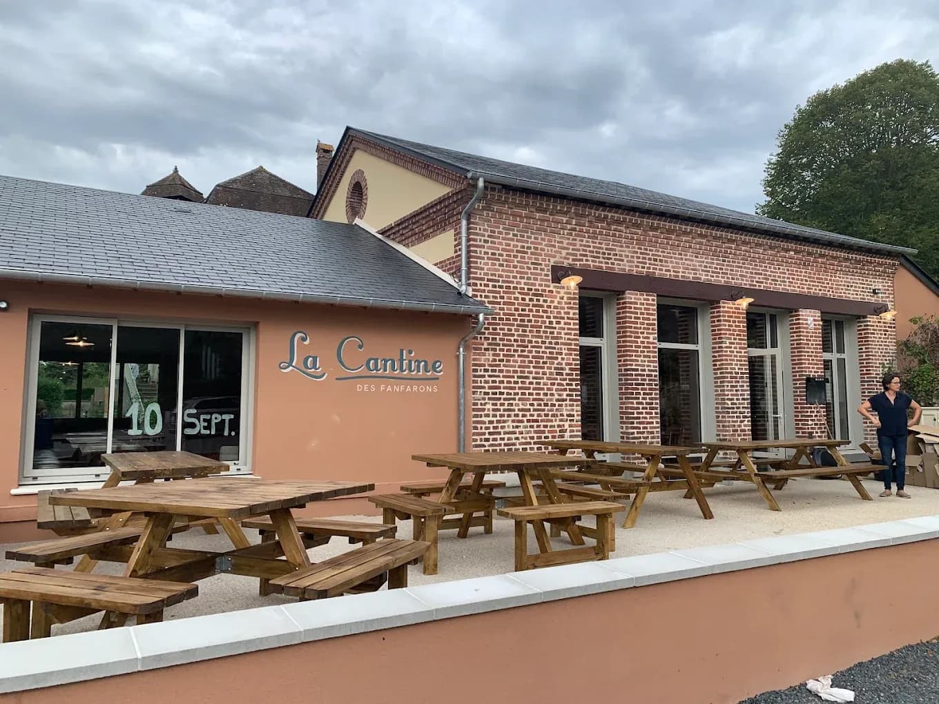 Façade en briques de La Cantine des Fanfarons à Manneville-la-Pipard avec sa terrasse et ses tables de pique-nique